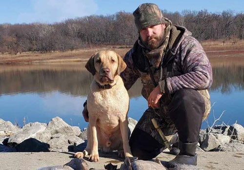  Hunter poses with dog in front of lake